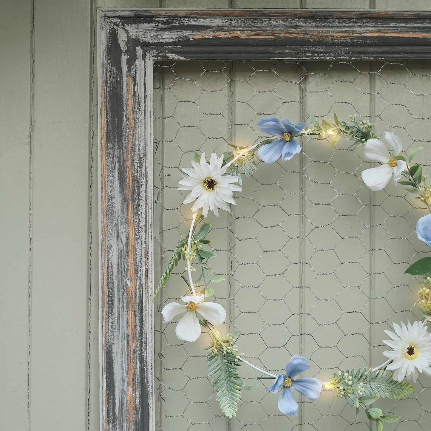 Beleuchteter Kranz und Girlande mit blauen und weißen Blüten